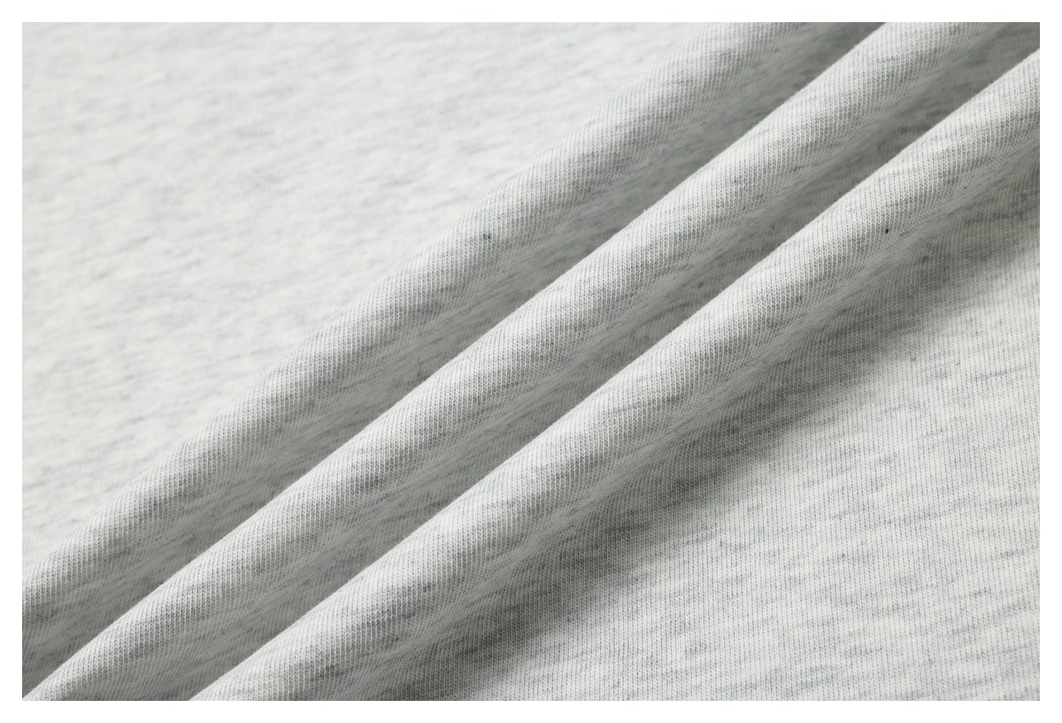 Close-up of light gray heathered knit fabric draped in diagonal folds.