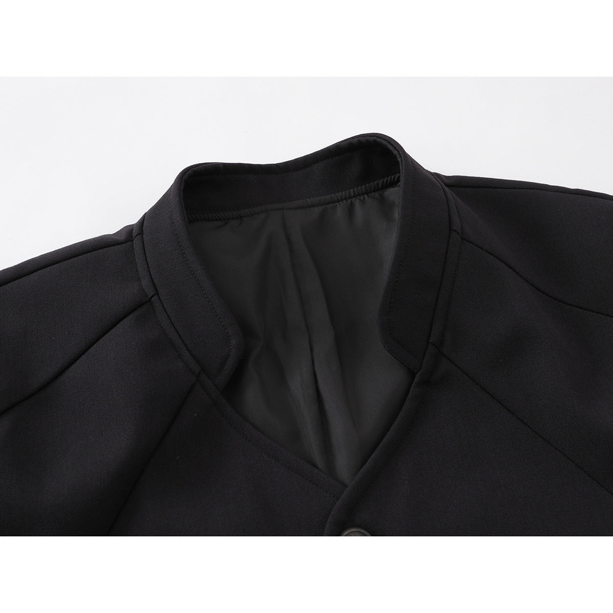 Close-up of a black jacket's stand collar, shoulder seams, and partially visible front button.