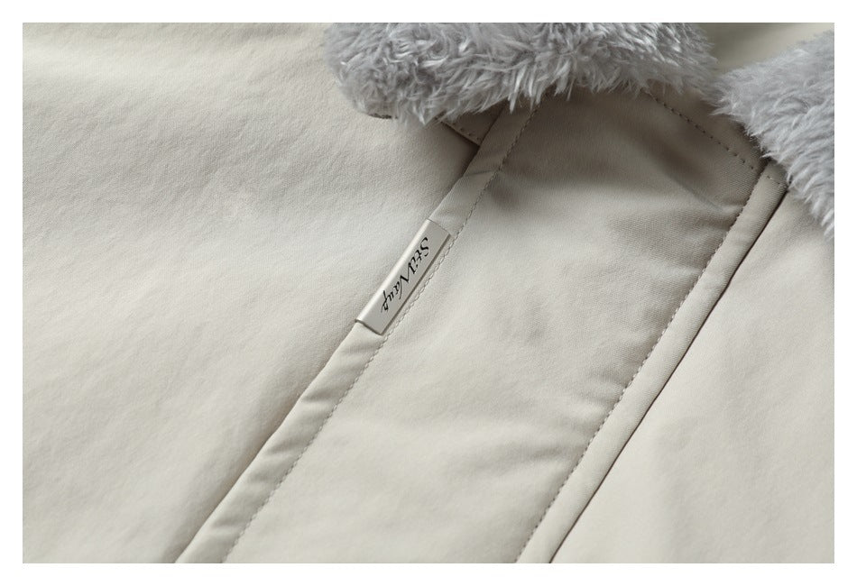 Close-up of a cream coat seam with a small sewn label and gray fluffy lining.