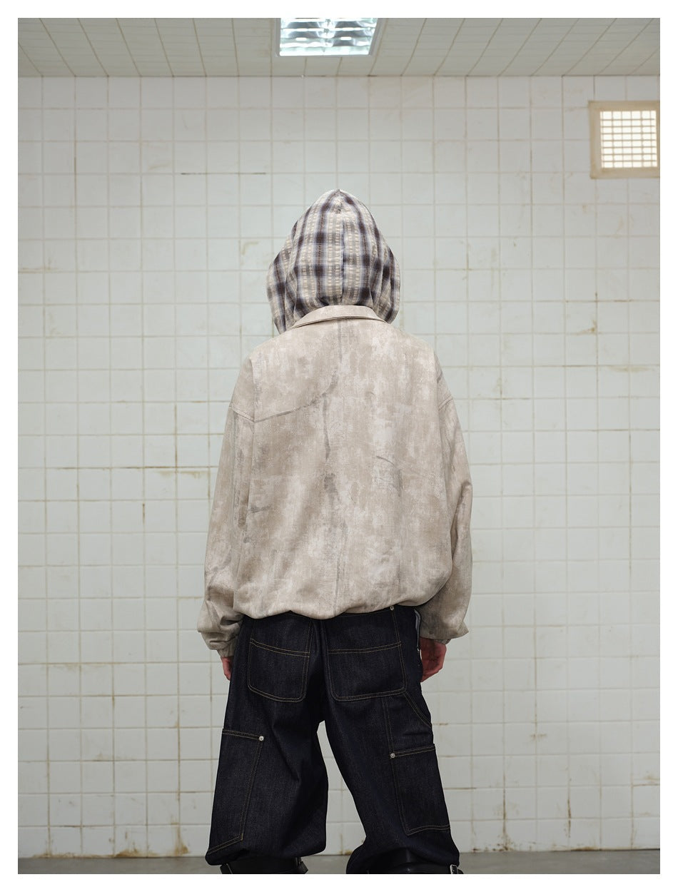 Back view of a model wearing a beige mottled jacket with a plaid hood and dark jeans.