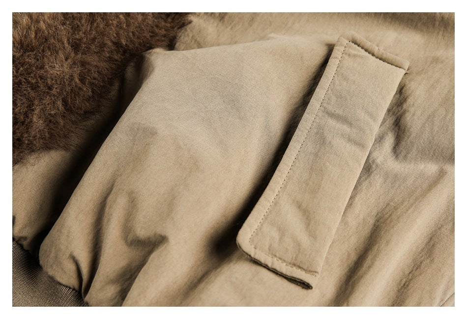 Close-up of a tan coat with a flap pocket and brown fur trim.