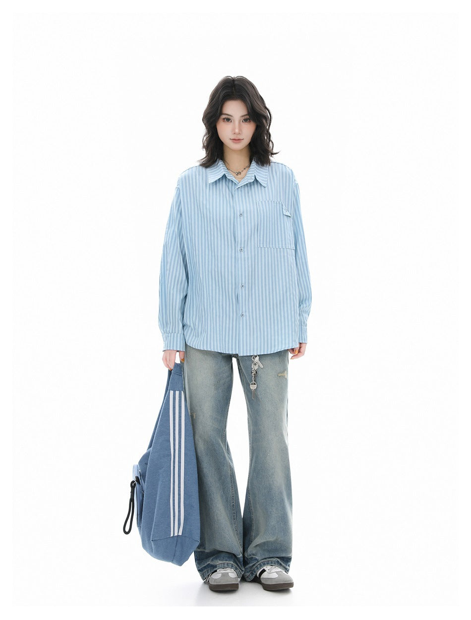 Full-length model wearing a light blue striped button-up shirt with loose gray jeans and sneakers.