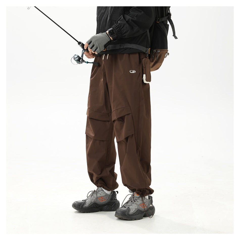 Angled front view of a model wearing loose dark brown cargo pants with layered thigh pockets.