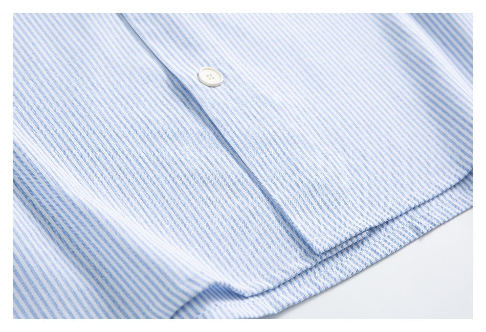 Close-up of a white shirt with fine blue stripes and a white button on the placket.