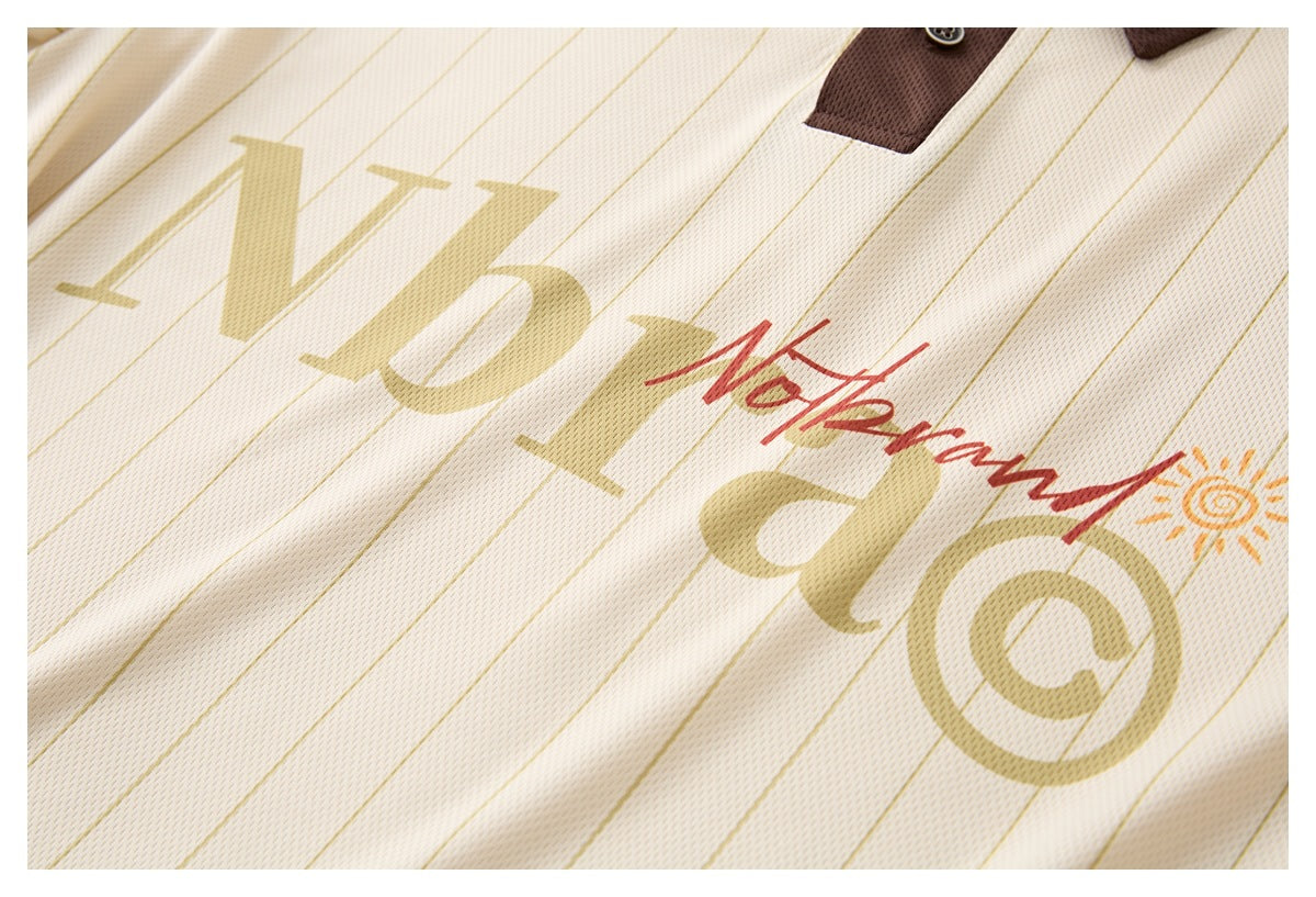 Close-up of cream pinstriped garment with oversized gold lettering, red script and an orange sun graphic.