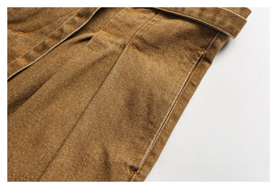 Close-up of the tan trousers' pleated front and stitched seams.