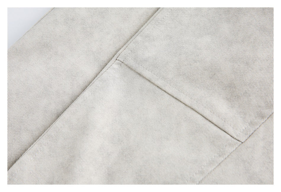 Close-up of a stitched panel seam on light gray jacket fabric.