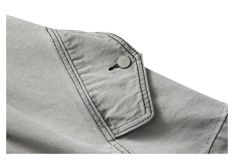Close-up of a light gray washed denim shorts cargo pocket with a flap and round button.