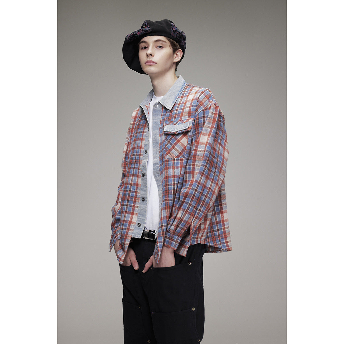 Model wearing a blue, rust and cream plaid button-up overshirt with a pale contrasting collar and chest pocket.
