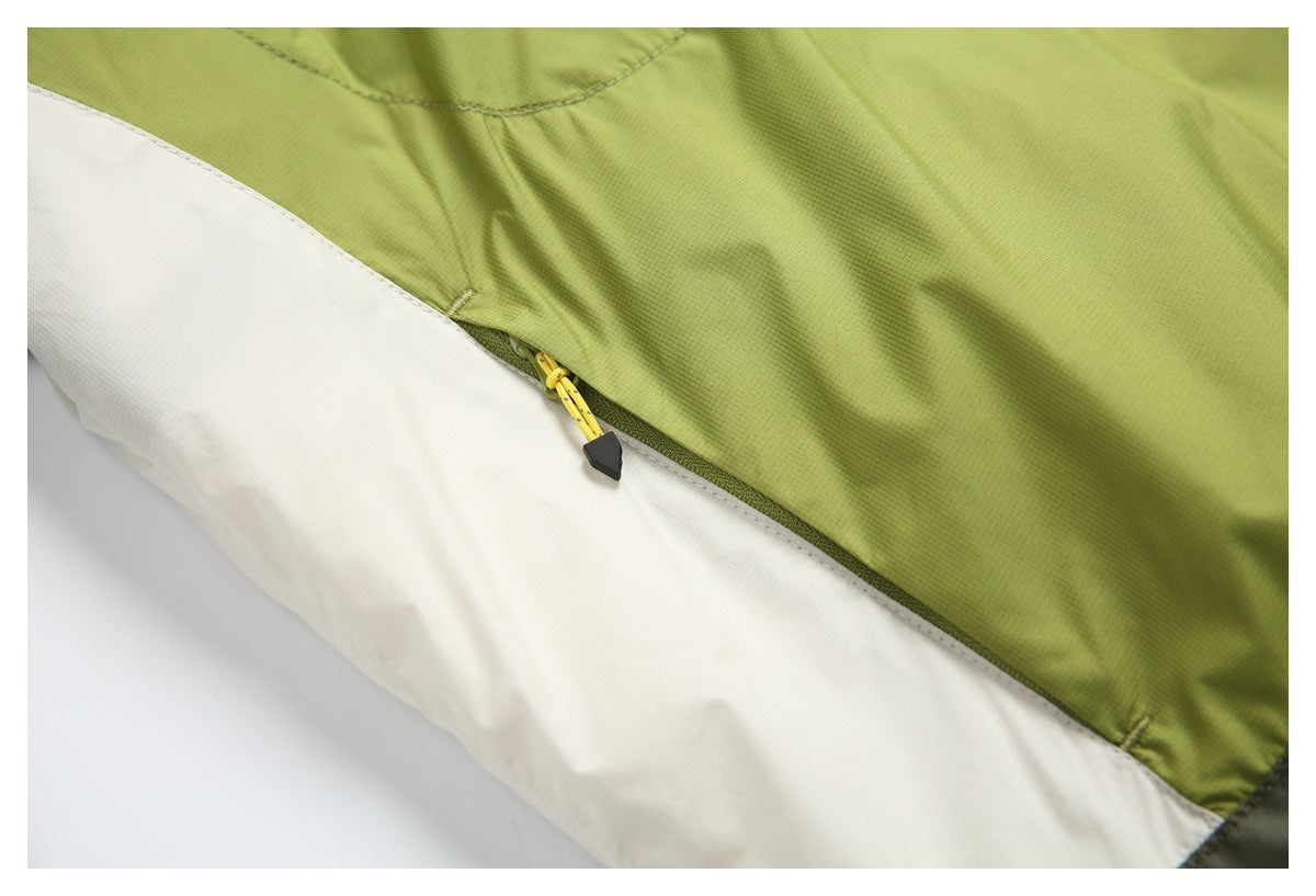 Close-up of a small yellow-pull zipper along the olive-green and white panels of a jacket.