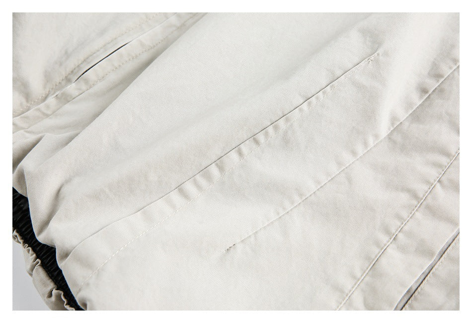 Close-up of cream garment panels with a long stitched seam and a gathered dark edge.