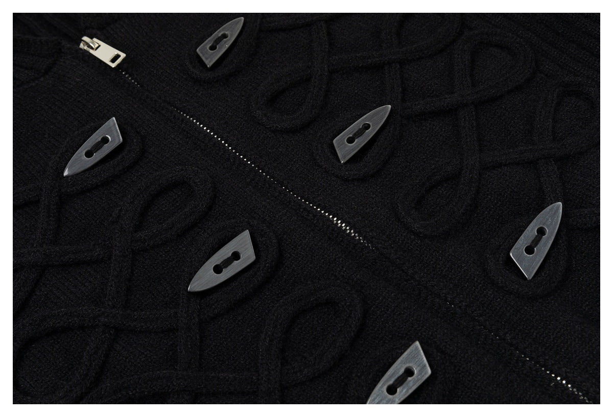 Close-up of a black cardigan’s raised loop pattern, toggle buttons, and diagonal zipper.