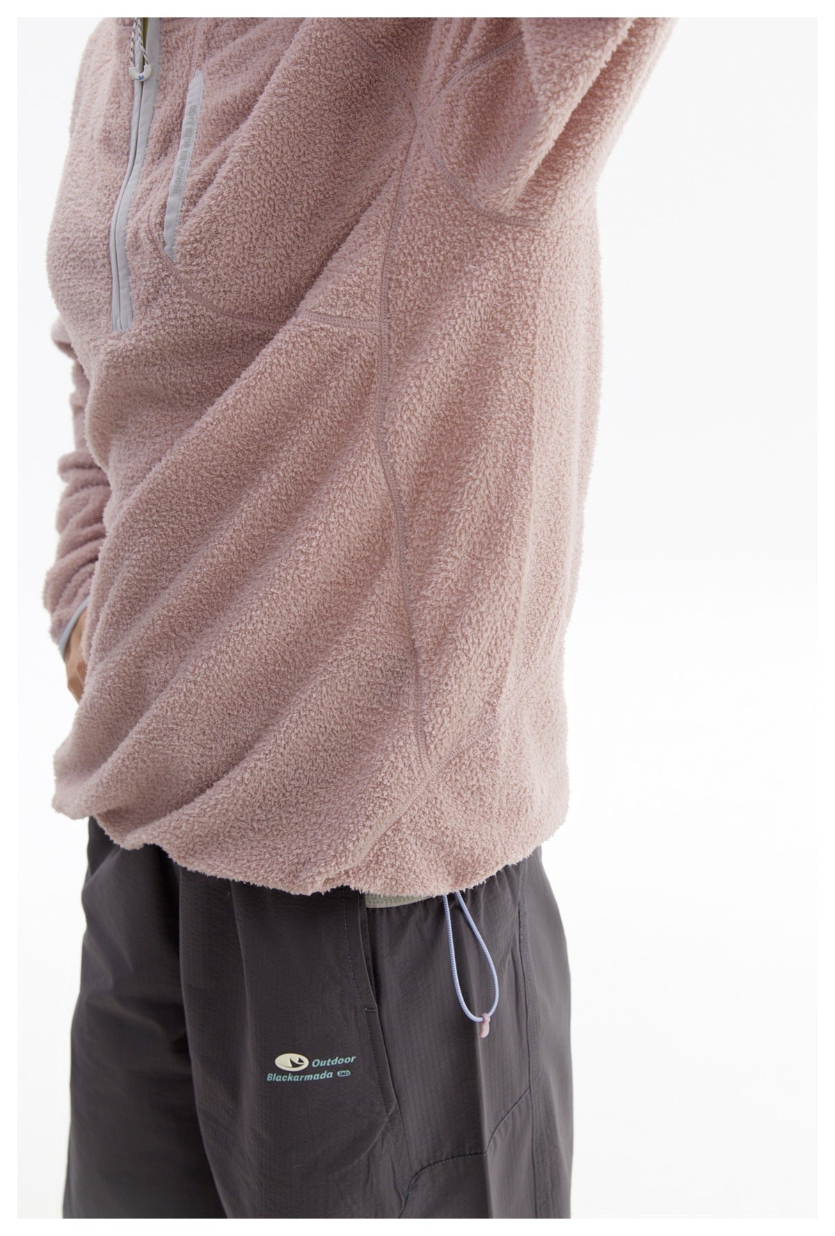 Side close-up of the pink fleece pullover showing its seams and hem drawcord.