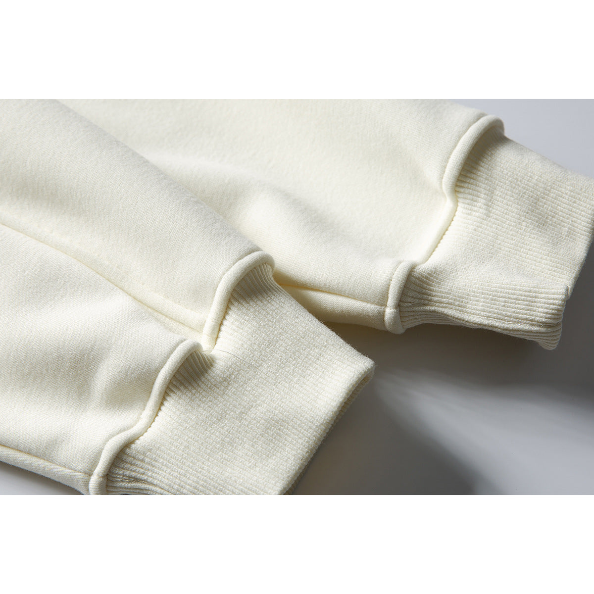 Close-up of an ivory hoodie’s sleeve cuffs and ribbed knit trim.