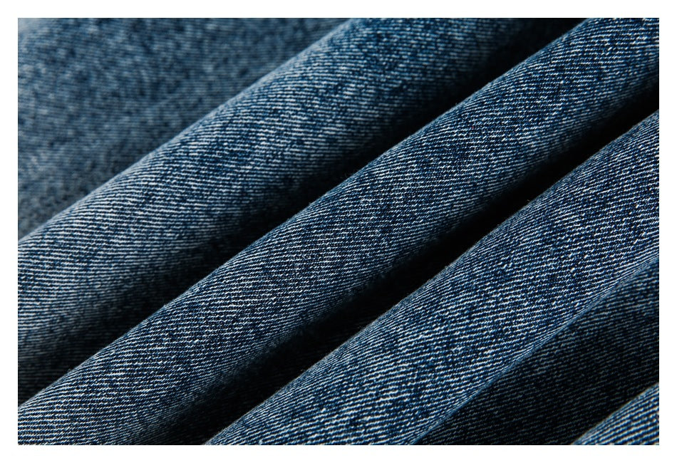 Close-up of dark blue denim arranged in soft folds, showing its diagonal weave.