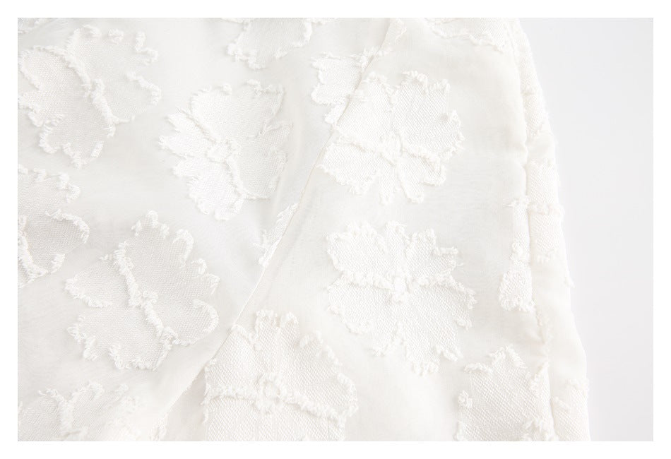Close-up of ivory fabric with raised floral motifs and a diagonal seam.