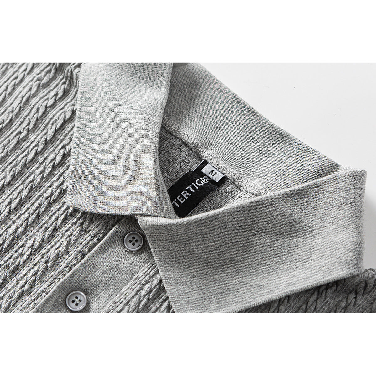 Close-up of a gray cable-textured polo shirt collar, two buttons, and an inside label.