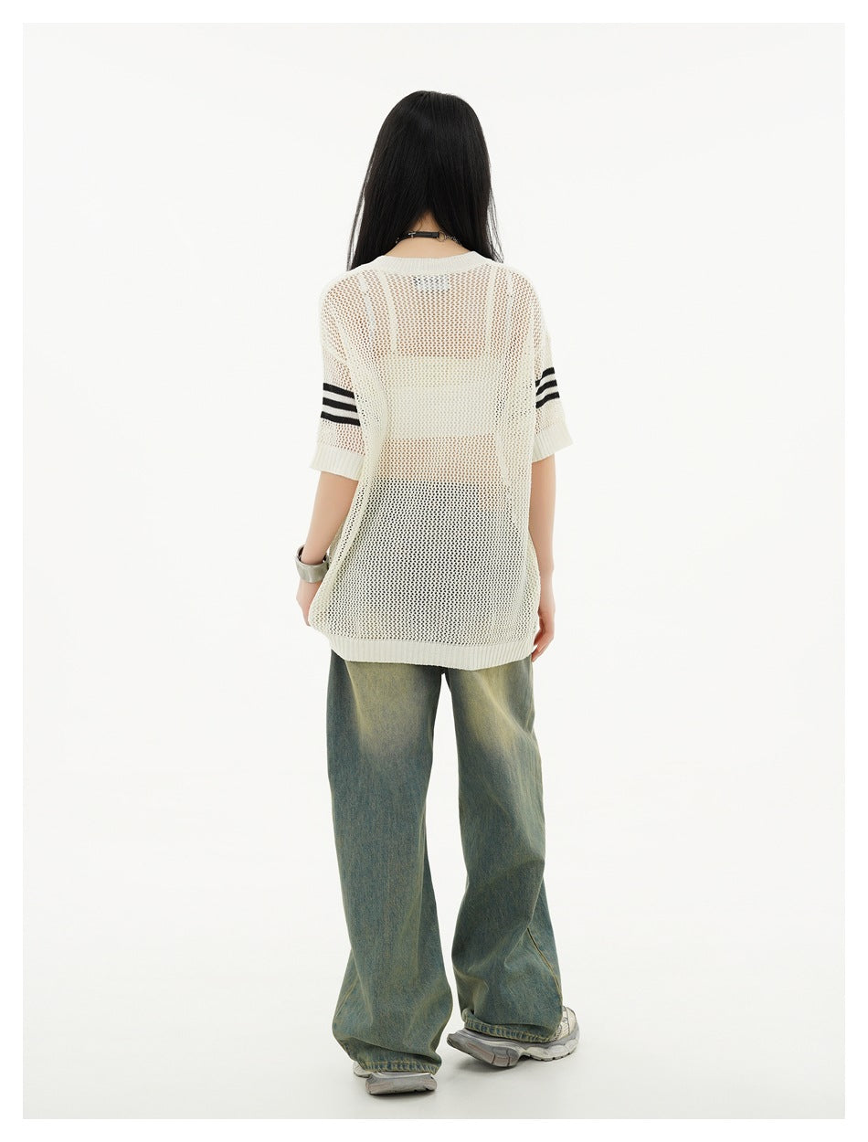 Back view of a model in an off-white open-knit short-sleeve top with black sleeve stripes and wide-leg jeans