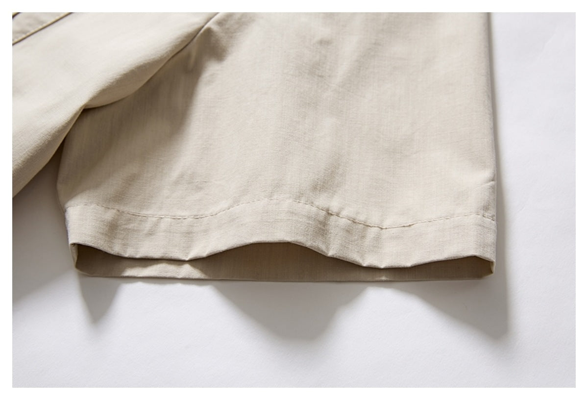 Close-up of the short sleeve and stitched hem of an ivory shirt laid flat.