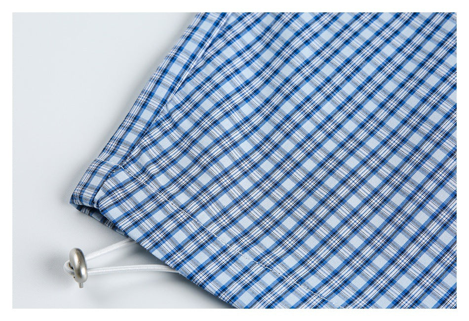 Close-up of a white drawcord with a metal toggle emerging from blue-and-white plaid fabric.