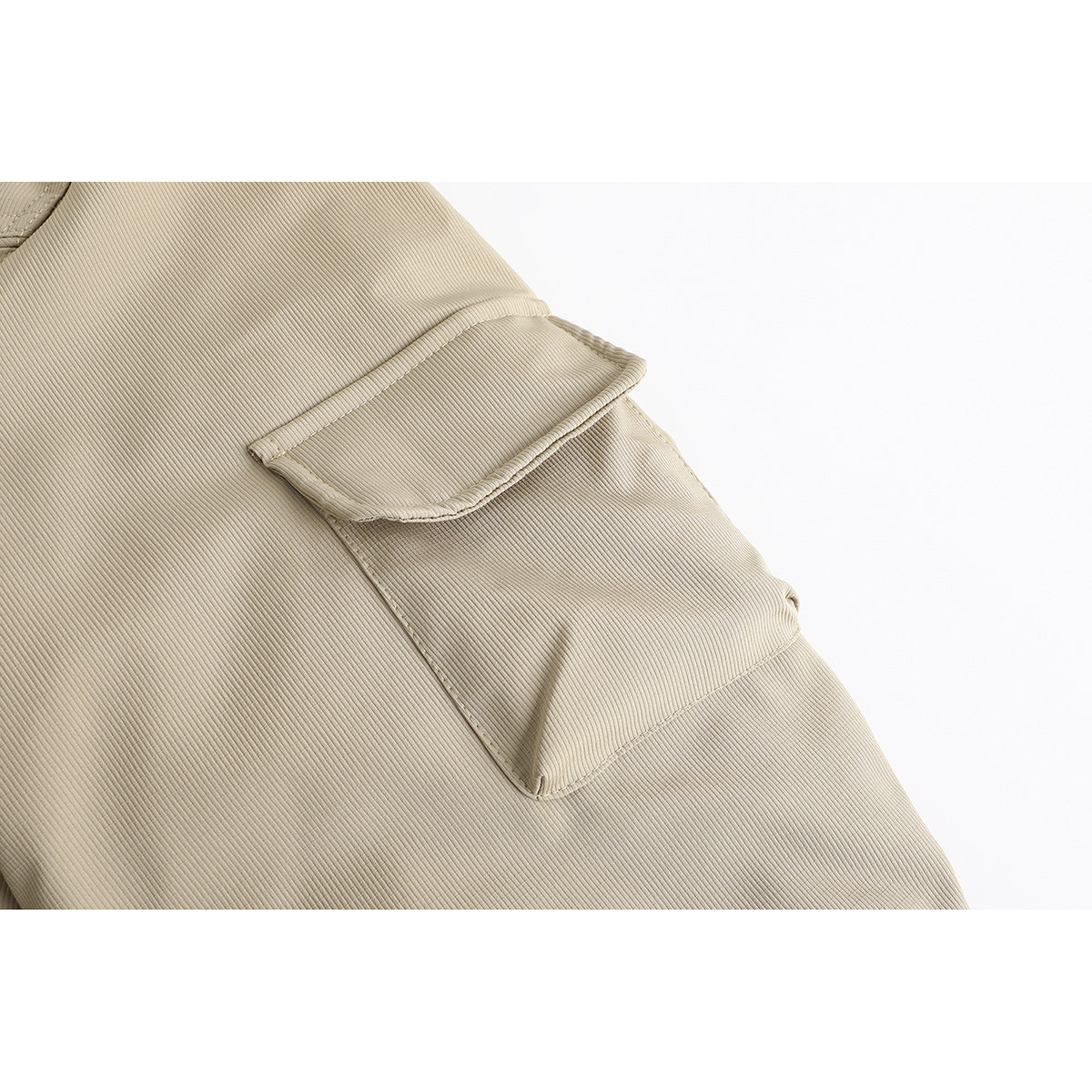 Close-up of a flap pocket and stitched panel on the beige jacket sleeve.