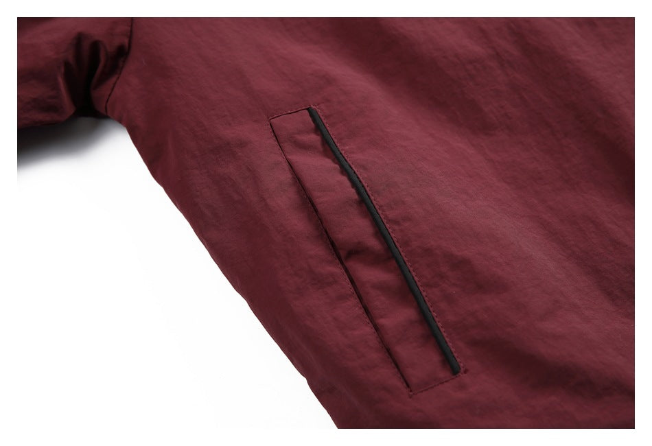 Close-up of a narrow vertical pocket with black trim on a burgundy jacket.