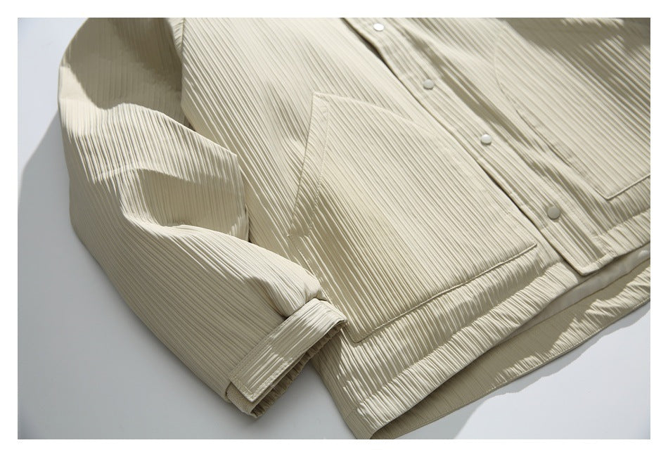 Close-up of the ivory pleated jacket’s front pocket, sleeve, and lower hem.