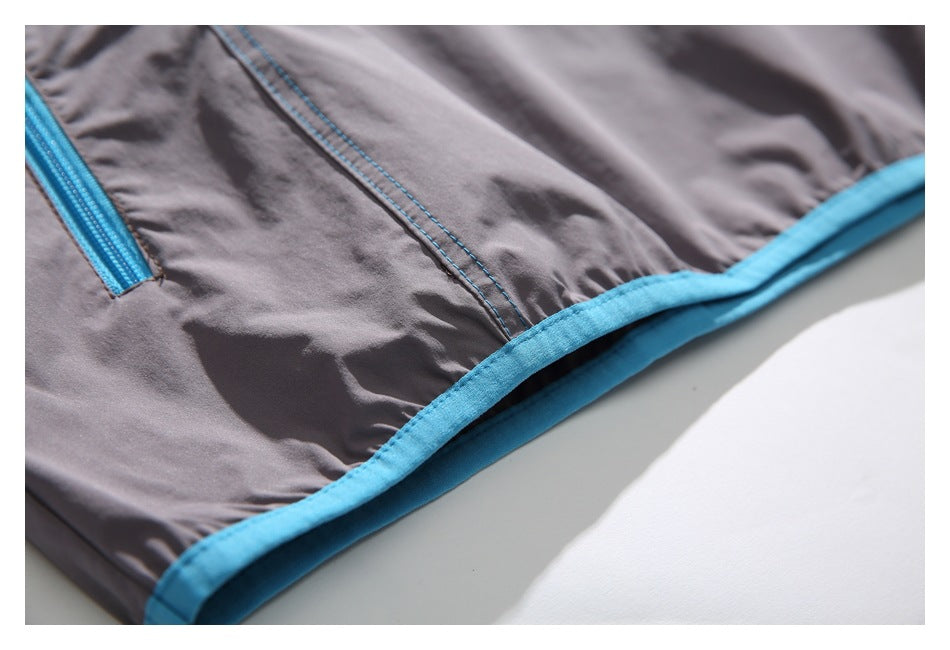Close-up of a gray garment hem with bright blue binding, blue stitching, and part of a blue zipper.