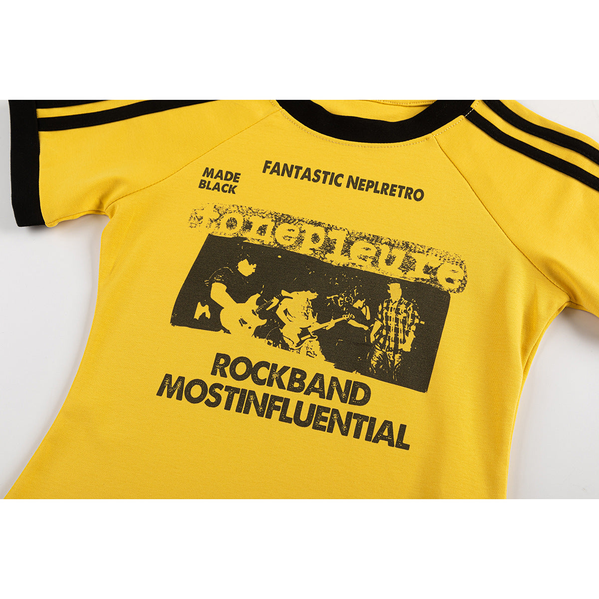 Close-up of a yellow T-shirt with black collar and shoulder stripes and a distressed black rock band graphic.