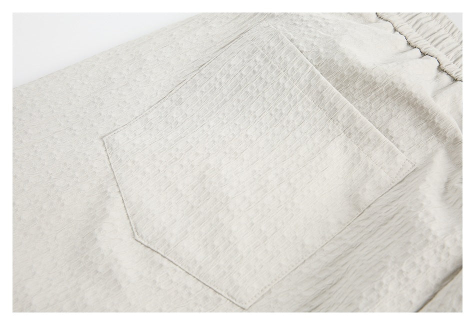 Close-up of a patch pocket on the off-white shorts, showing the textured fabric and stitching.