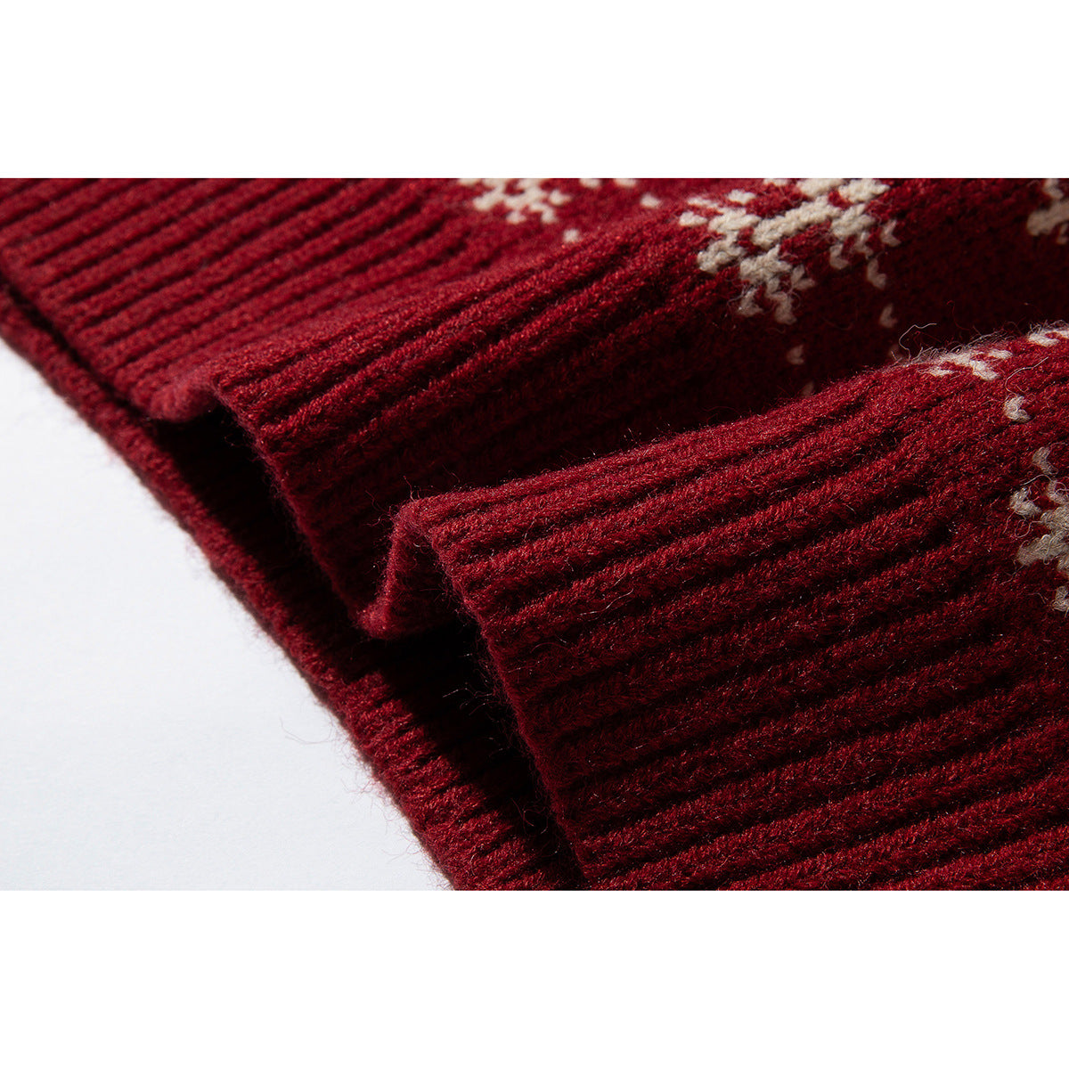 Close-up of burgundy ribbed knit edges with part of a cream sweater pattern.