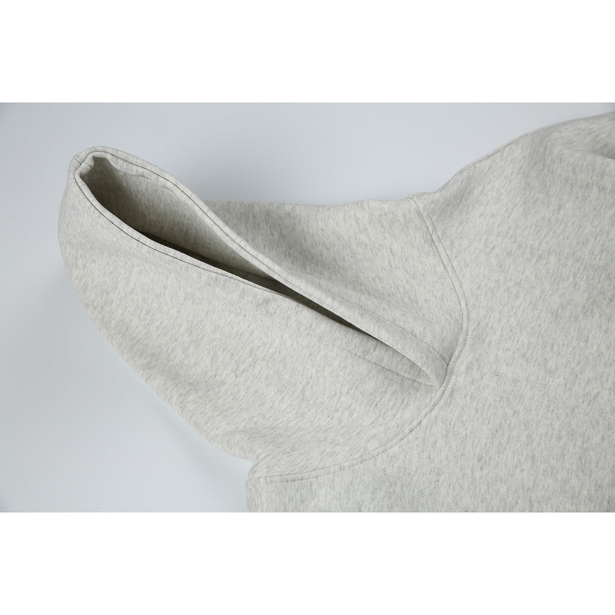 Close-up of a light heather-gray hoodie showing the hood opening and its stitched seams.