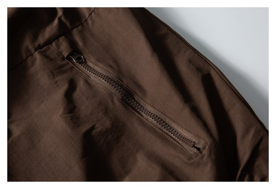 Close-up of a diagonal zip pocket on a dark brown jacket.
