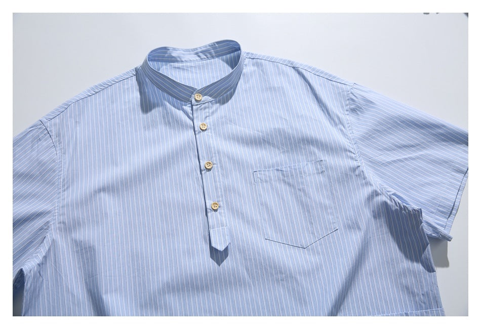 Light blue striped short-sleeve shirt laid flat, with a stand collar, cream buttons and chest pocket.