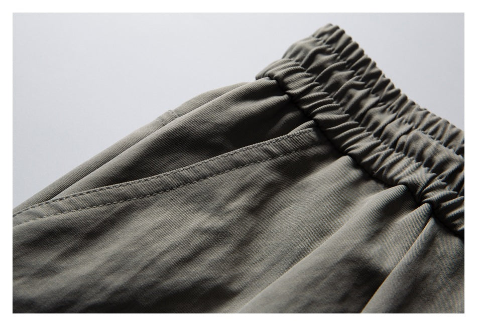 Close-up of gray shorts showing the gathered elastic waistband and slanted front pocket.