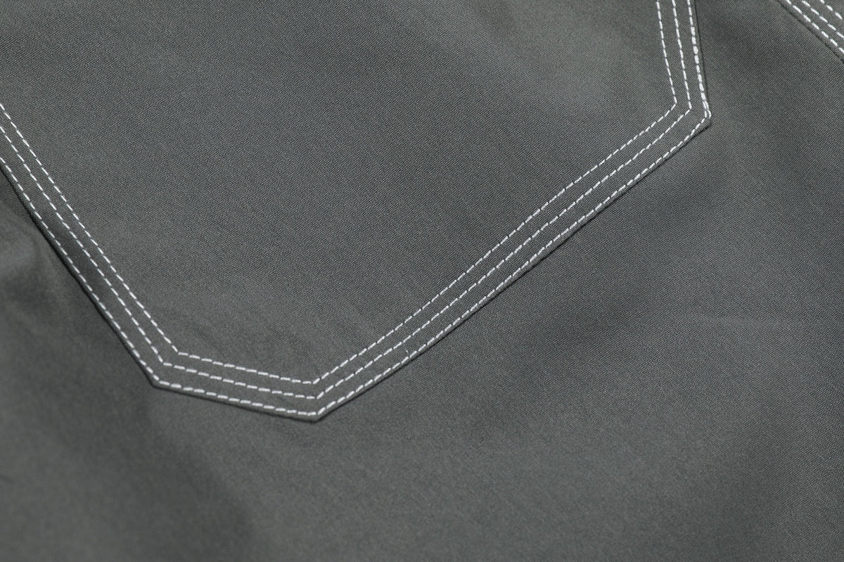 Close-up of an angular pocket edge with double white stitching on charcoal gray pants.