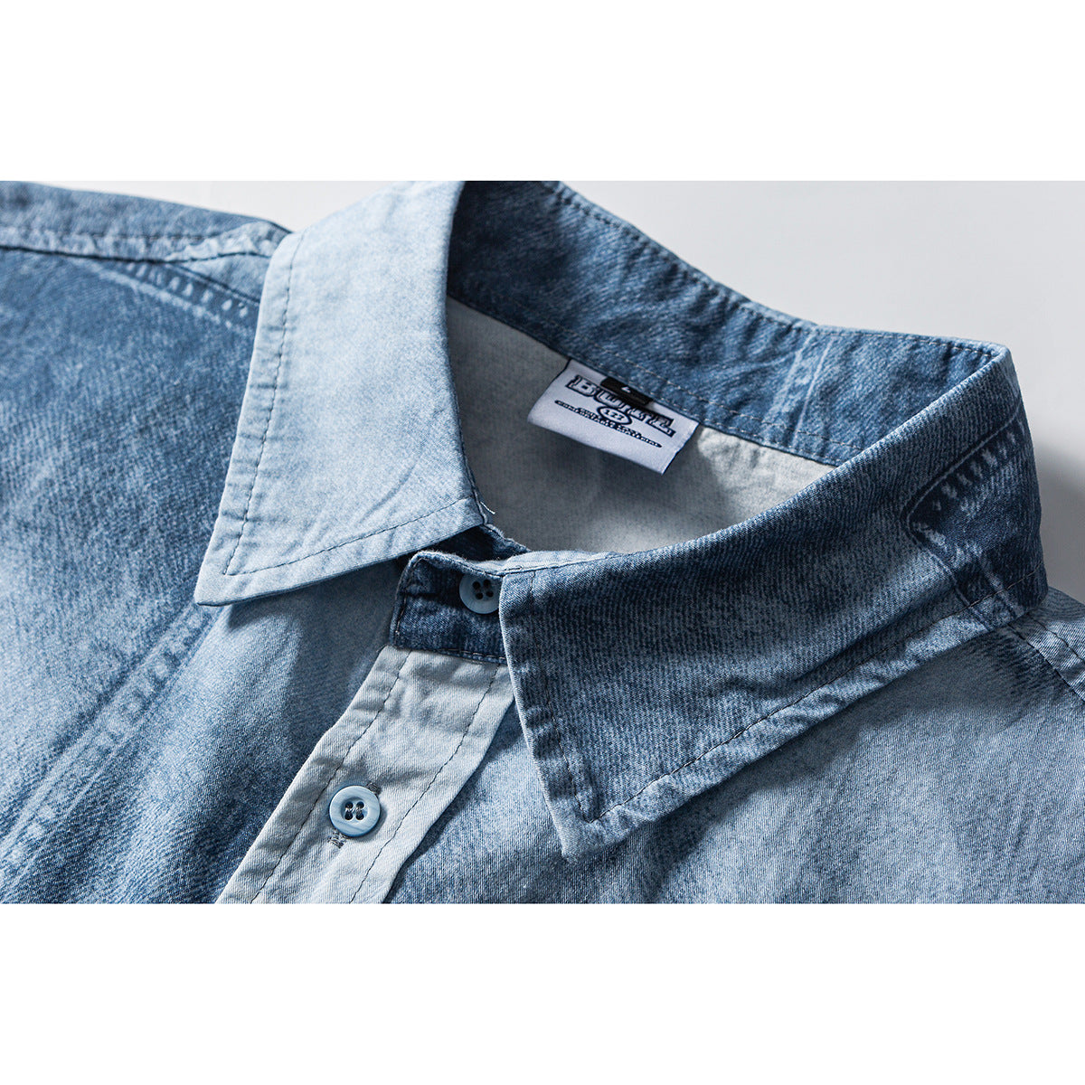 Close-up of a blue washed shirt collar, button placket, and sewn-in neck label.