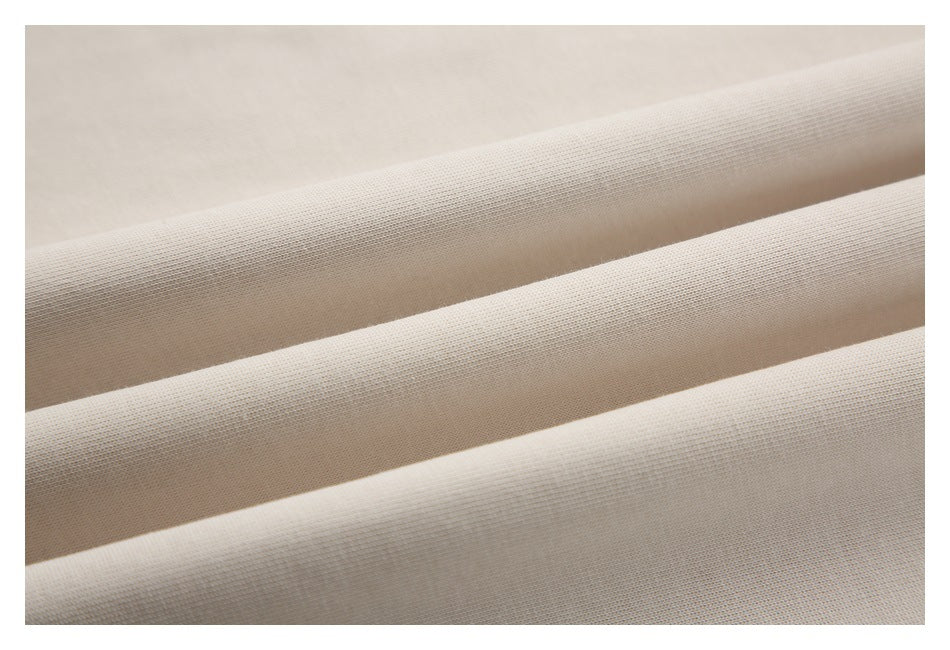 Close-up of off-white fabric arranged in soft folds, showing its fine surface texture.
