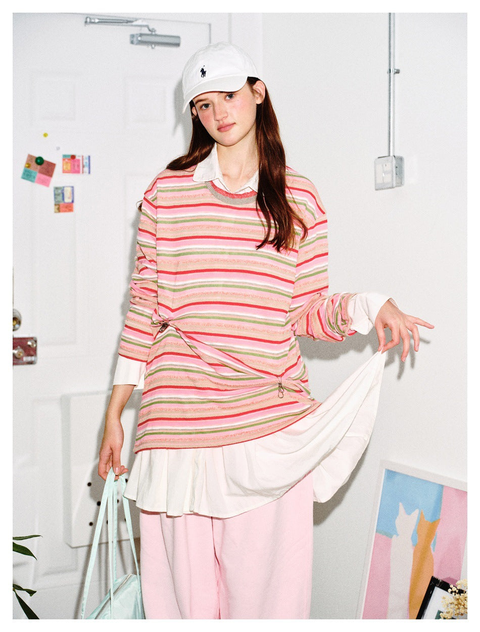 Model wearing pink striped long-sleeve top over a white shirt, holding a mint bag and lifting a white skirt