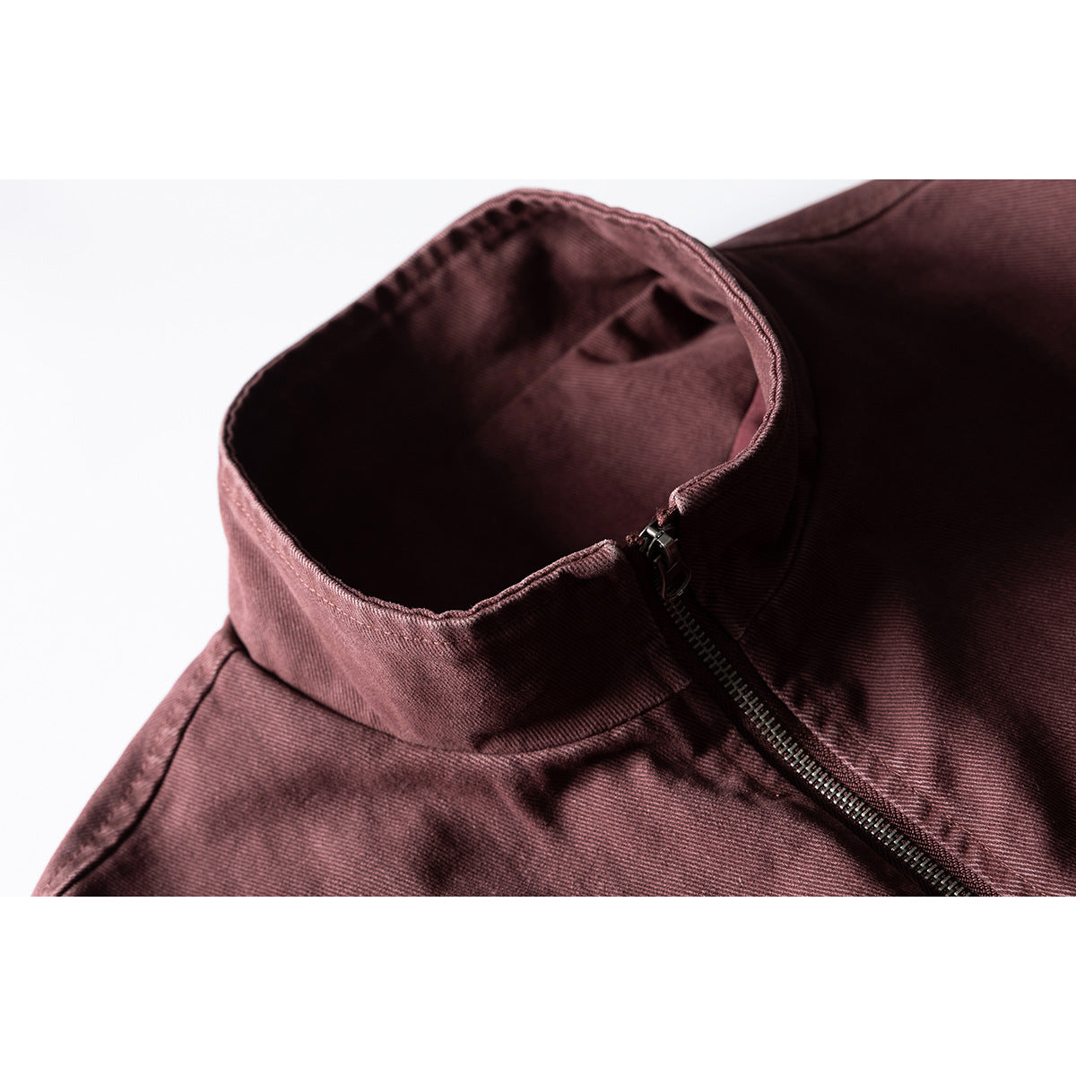 Close-up of a burgundy jacket's stand collar and diagonal front zipper.