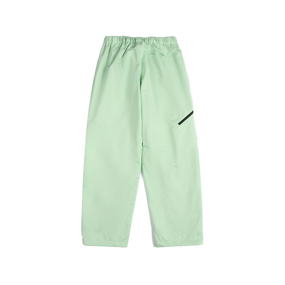 Back view of pale mint loose-fit pants with an elastic waist, small rear pocket, and diagonal black leg detail.