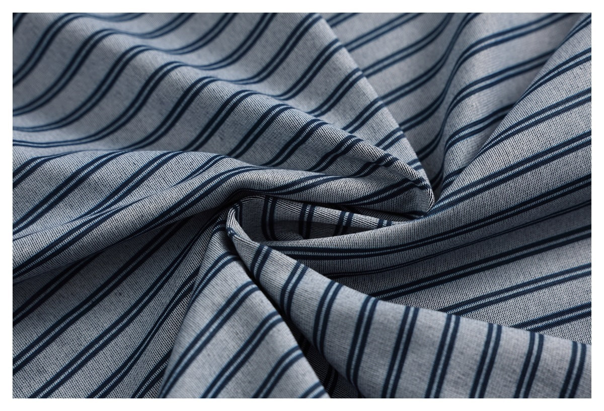Close-up of gray-blue fabric gathered into folds, displaying its repeating narrow navy stripe pattern.
