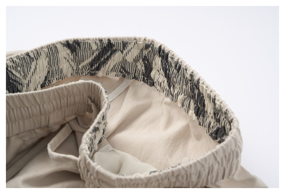 Inside view of the cream garment's gathered waistband, with a dark abstract patterned inner band.