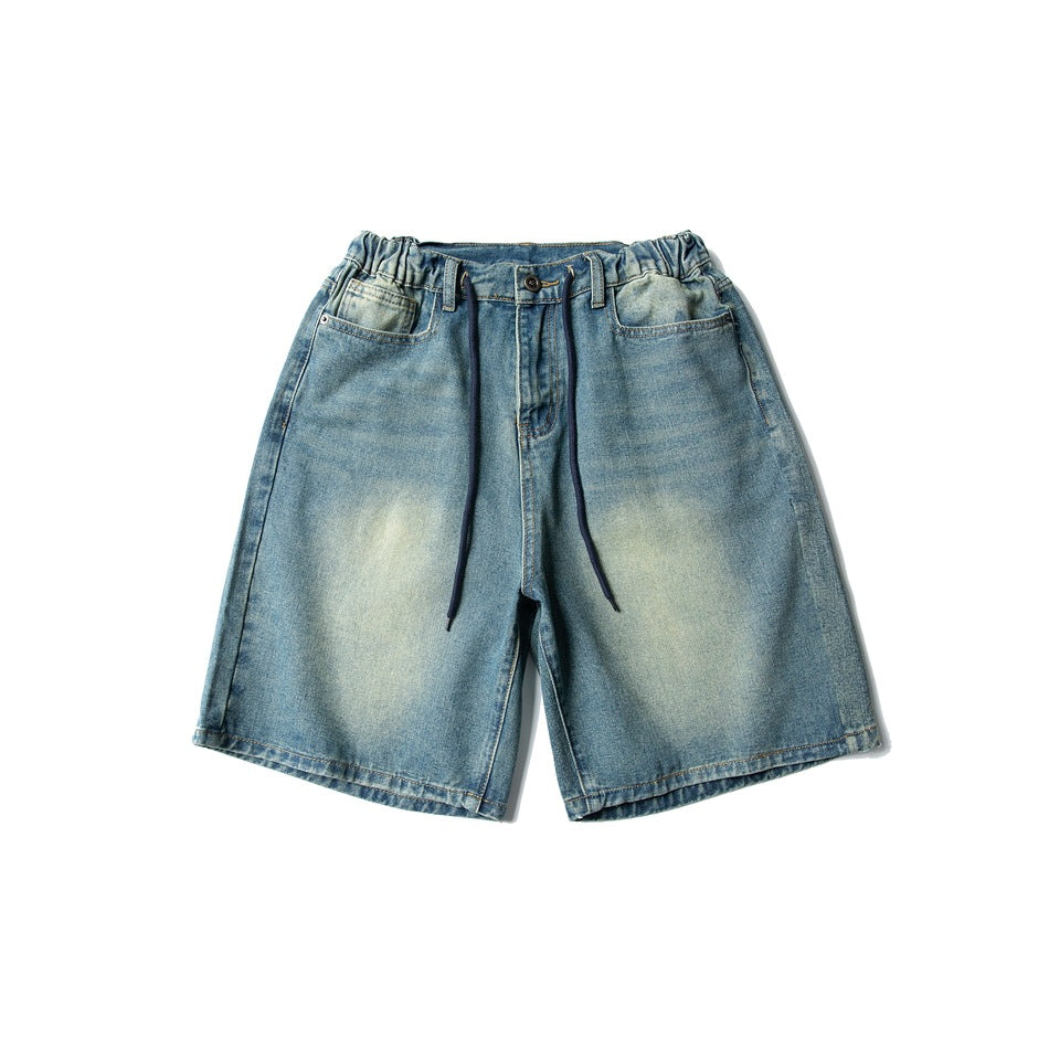 Front of faded blue denim shorts with elastic waistband, navy drawstring, button fly and front pockets