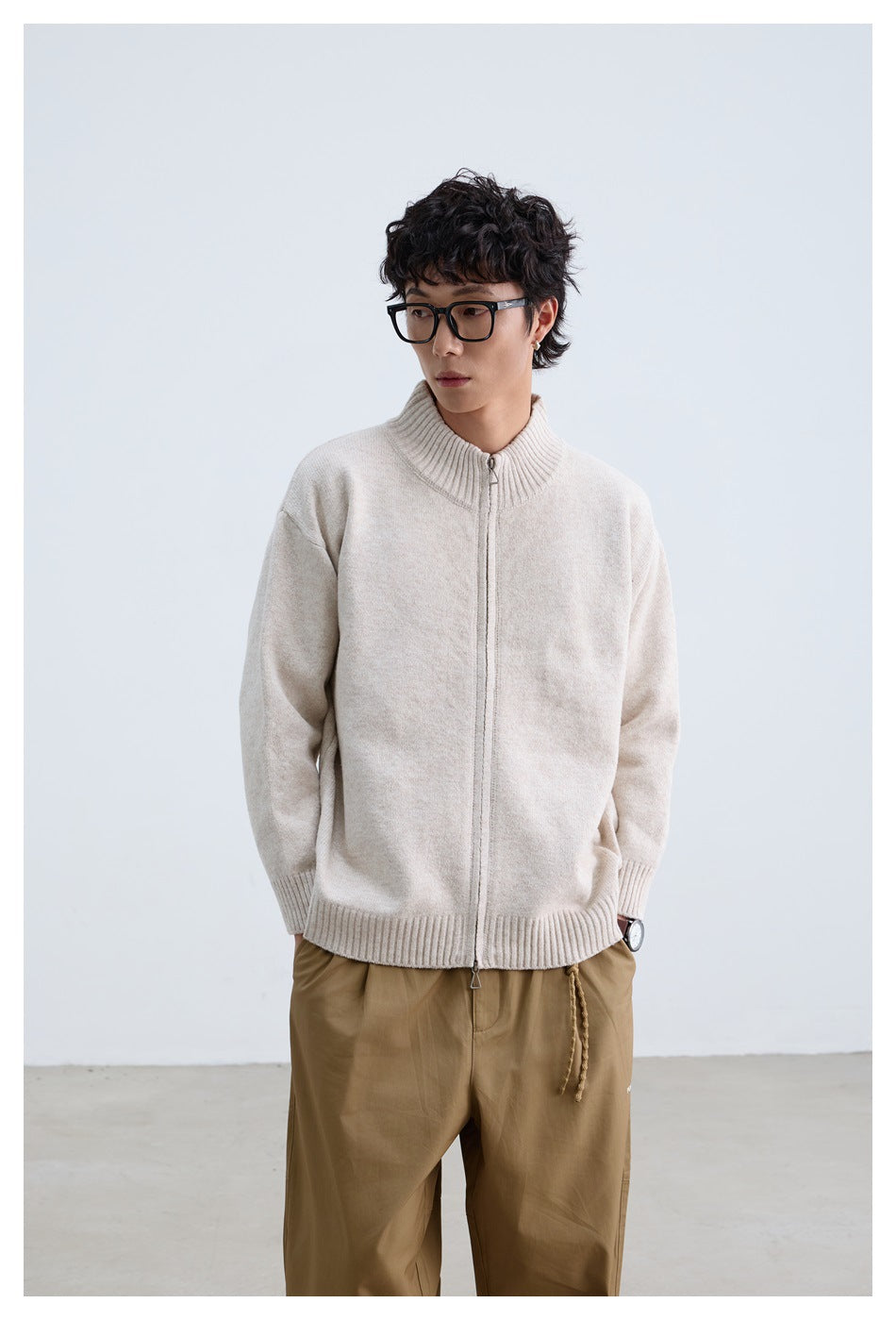 Front view of a man wearing an ivory zip-front knit sweater with ribbed collar, cuffs, and hem.