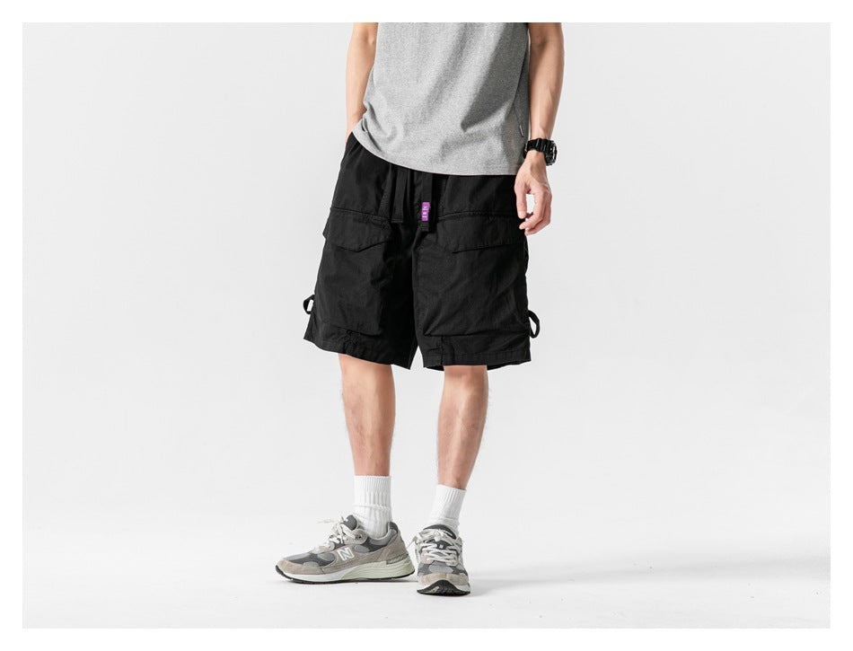 Front view of a model wearing black cargo shorts with roomy pockets and side loops.