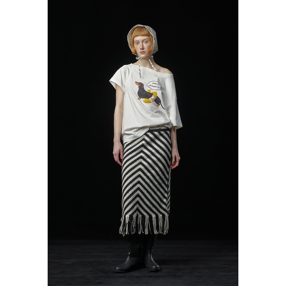 Model wearing a white off-shoulder graphic T-shirt and a black-and-white chevron skirt with fringe.