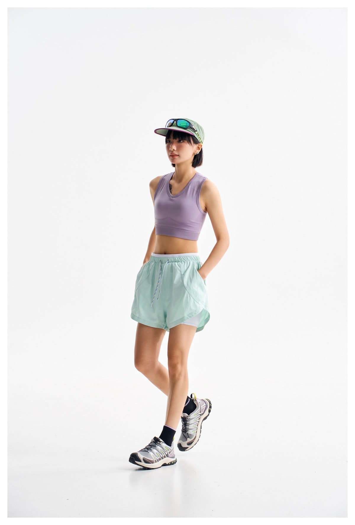 Three-quarter view of a model wearing a lavender V-neck crop tank and mint drawstring shorts.