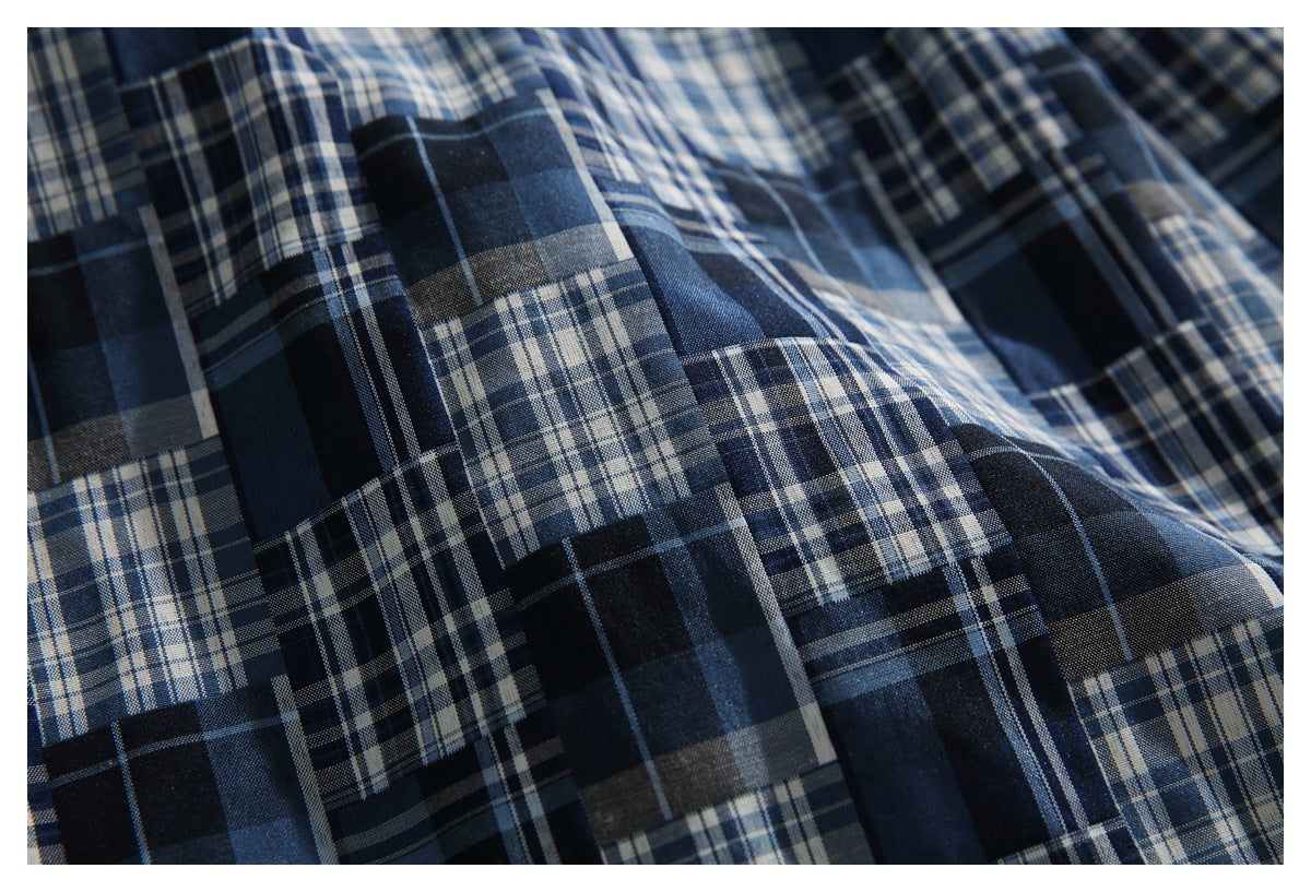 Close-up of navy, blue, gray, and white plaid fabric with overlapping checks and visible woven texture.