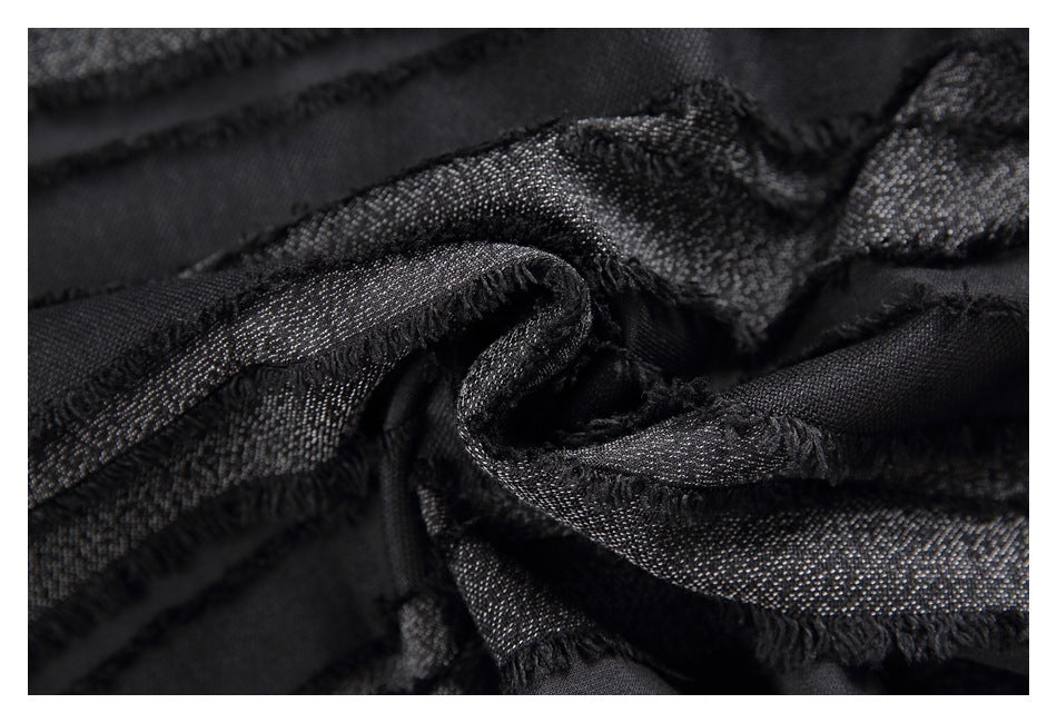 Macro view of gathered black fabric with frayed edges and subtle metallic flecks.